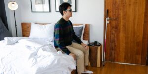 침대 끝에 앉아 편안하게 발목 운동을 하는 시니어의 모습