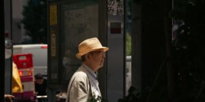 버스 정류장에서 스마트폰을 사용하는 시니어