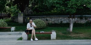 공원에서 보조 배터리로 스마트폰을 충전하며 휴식 중인 시니어의 모습