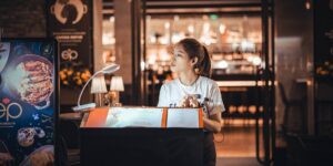 어두운 식당에서 LED 조명 돋보기로 메뉴판을 확인하는 시니어의 손