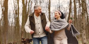 가을 정취가 가득한 숲길을 걷는 건강한 시니어 부부의 모습